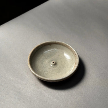Small ceramic dish on a gray surface with a black background