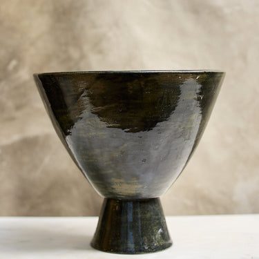 Black ceramic bowl on a white surface with a beige background