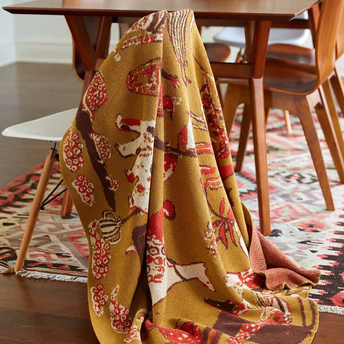 Patterned blanket draped over a wooden table in a dining room setting