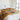 Bed with a colorful floral blanket in a room with a window and wooden beams.