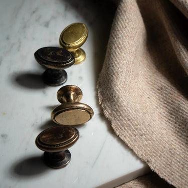 Set of vintage-style cabinet knobs on a marble surface with fabric in the background