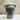 Green ceramic vase with two handles on a white surface and beige background