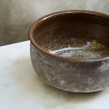 Brown ceramic bowl on a marble surface with a neutral background