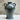 Black ceramic vase with handles on a white surface and beige background