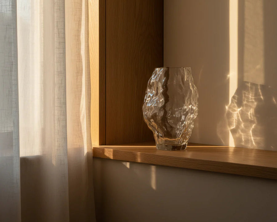 Glass vase on a wooden shelf with soft lighting and shadows